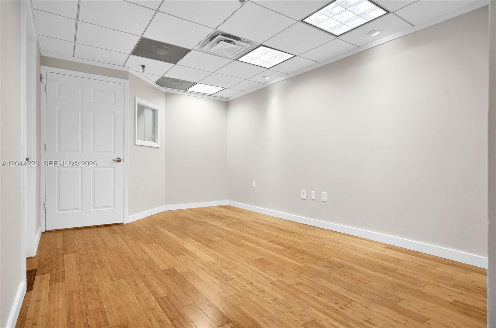 An empty office room features light wood flooring, white walls, and a drop ceiling — 2150 SW 22nd St # 7A, Miami FL 33145, MIAMI, FL