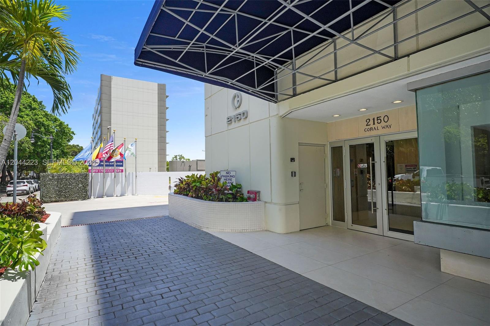 The exterior entrance of a commercial building features a blue awning and glass doors — 2150 SW 22nd St # 7A, Miami FL 33145, MIAMI, FL