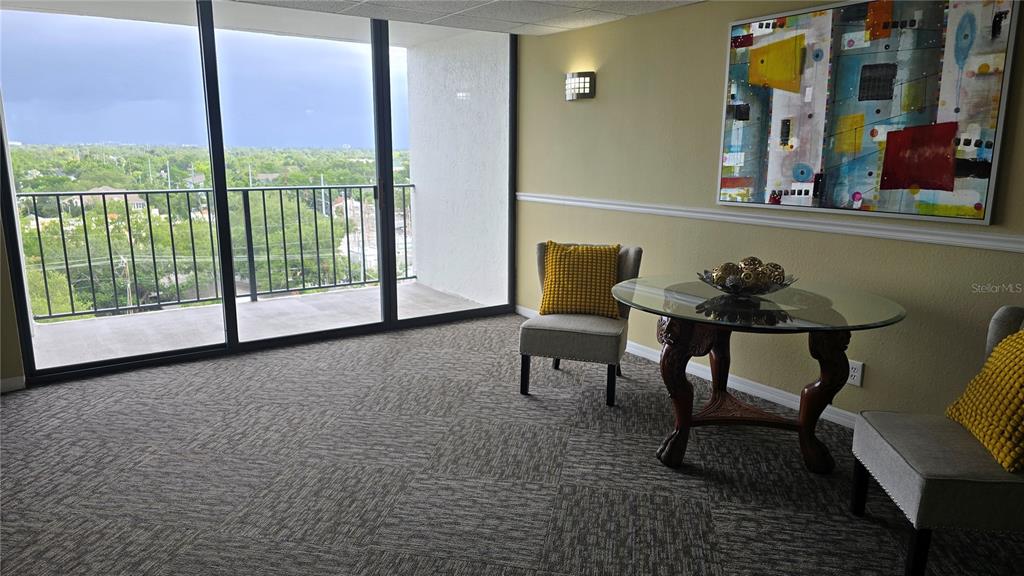 A room with a glass-topped table, two chairs, and a balcony overlooking a city view — 3211 W SWANN AVENUE UNIT 1005, TAMPA, FL