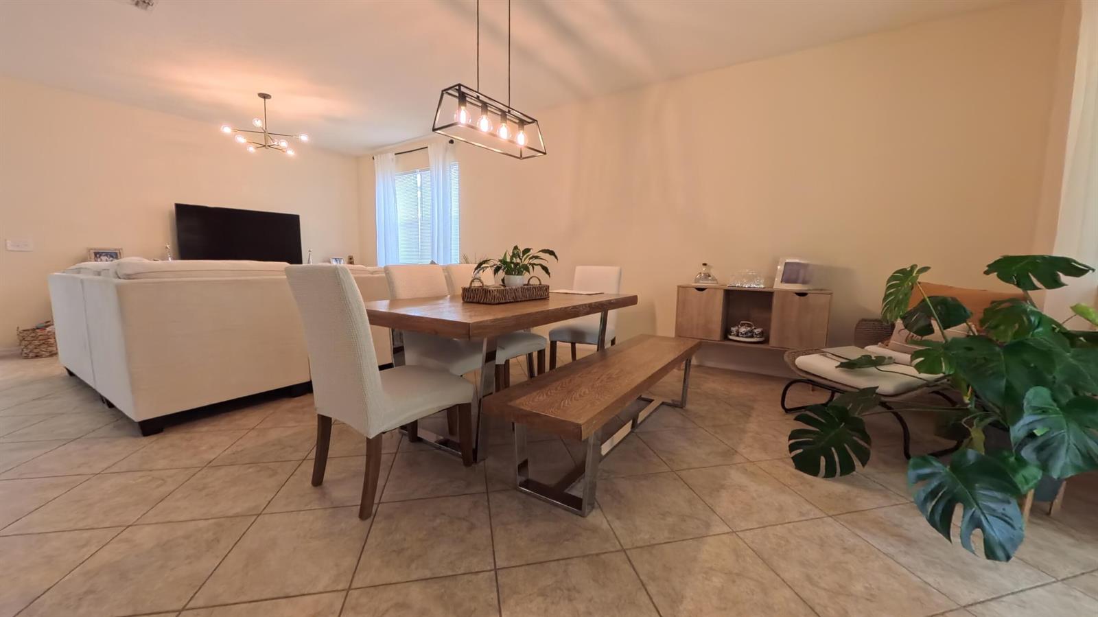 A dining area with a wooden table, bench, chairs, and a pendant light fixture — 8809 Arrabida Lane, Orlando FL 32836, ORLANDO, FL