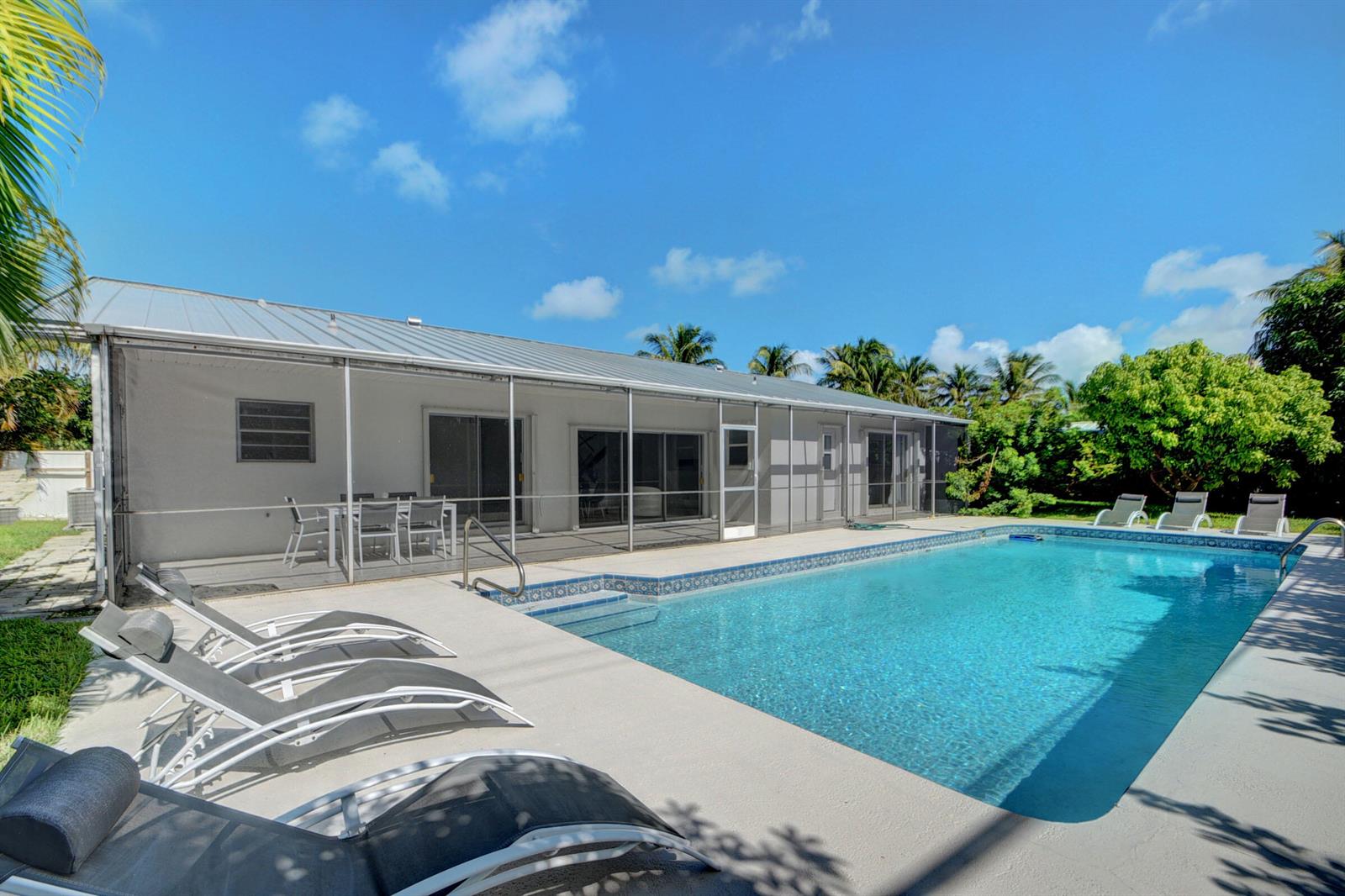 A swimming pool sits on a patio next to a house with a screened-in porch — 1171 Bimini Lane, Singer Island FL 33404, SINGER ISLAND, FL
