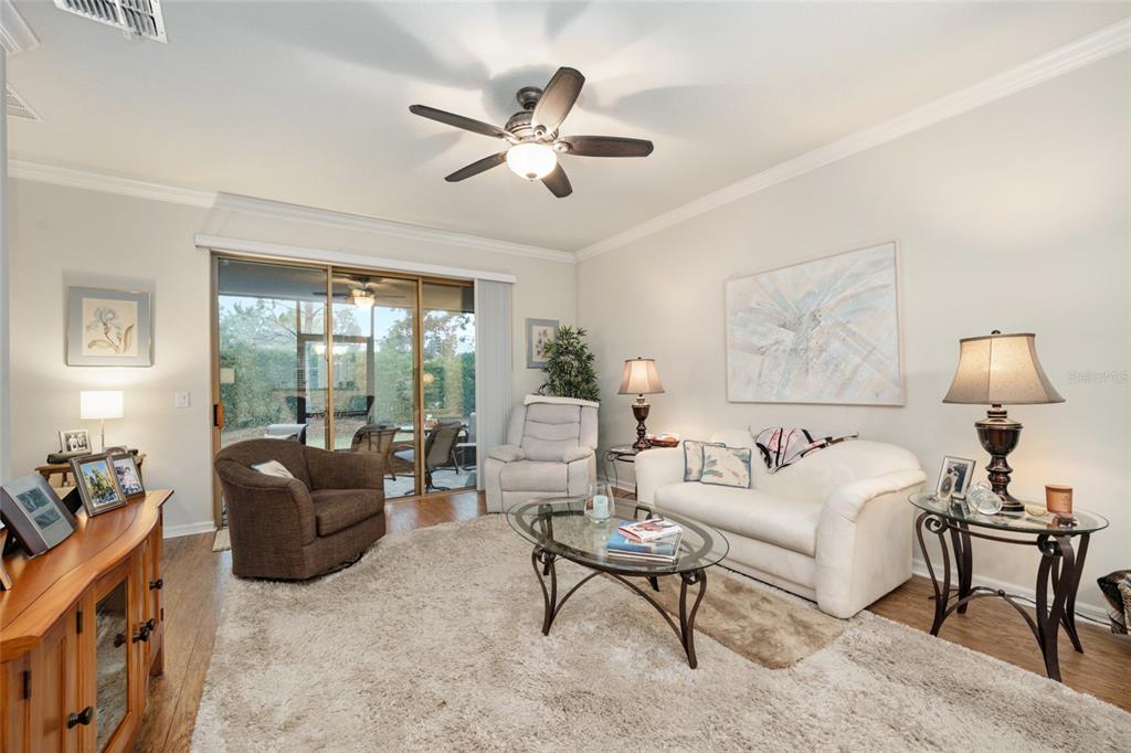 A living room features a beige rug, white sofa, brown armchair, and sliding glass doors — 9497 SW 76TH STREET, OCALA, FL
