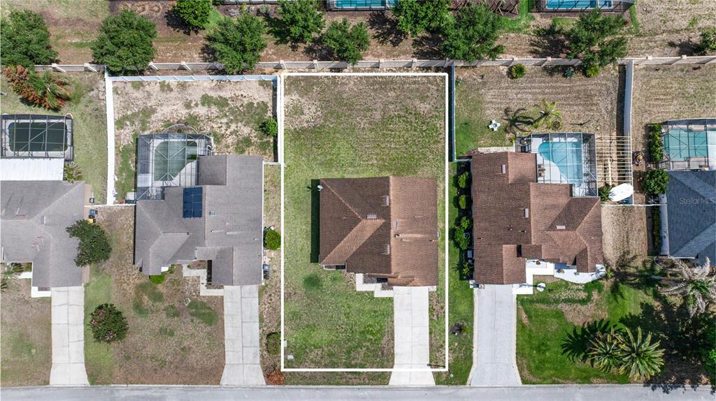 An aerial view shows a single-family house with a large backyard on a residential lot — 437 VIA DEL SOL DRIVE, DAVENPORT, FL