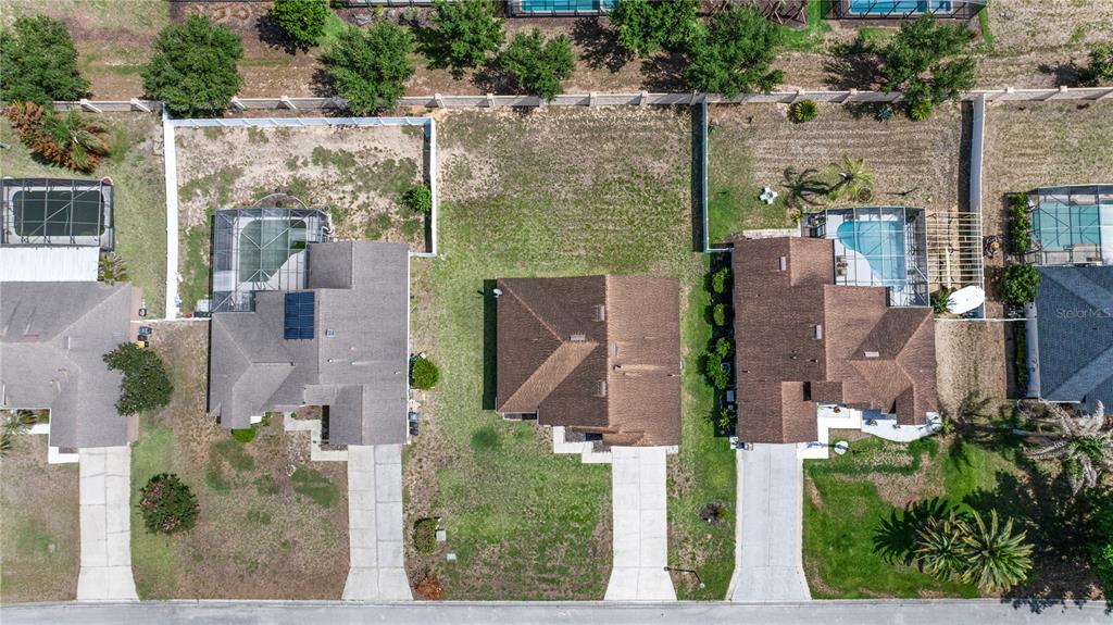 An aerial view shows three suburban houses with driveways, swimming pools, and fenced backyards — 437 VIA DEL SOL DRIVE, DAVENPORT, FL