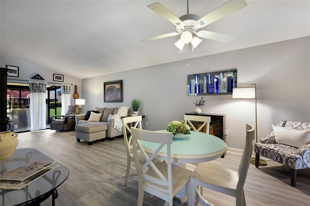 A living and dining area features light wood-look flooring, a ceiling fan, and neutral walls — 1218 56TH STREET W UNIT 1218, BRADENTON, FL
