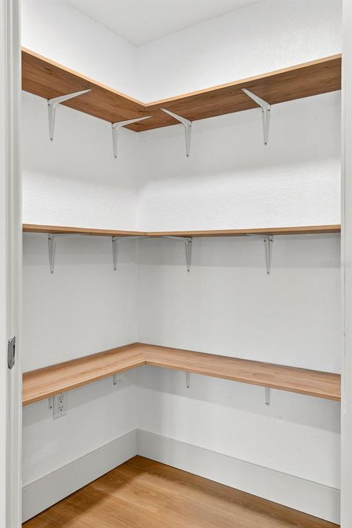 A walk-in pantry features white walls, light wood-tone shelving, and white metal support brackets — 6306 37TH AVENUE W, BRADENTON, FL