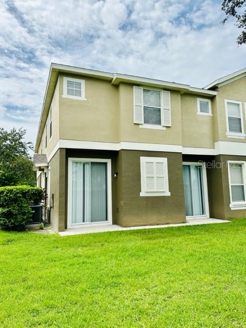 The exterior of a two-story tan townhouse features sliding glass doors and white-framed windows — 1953 ESTANCIA CIRCLE UNIT C, KISSIMMEE, FL
