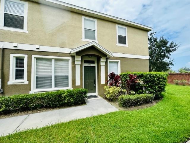 A two-story tan townhouse features a green front door and a manicured lawn — 1953 ESTANCIA CIRCLE UNIT C, KISSIMMEE, FL