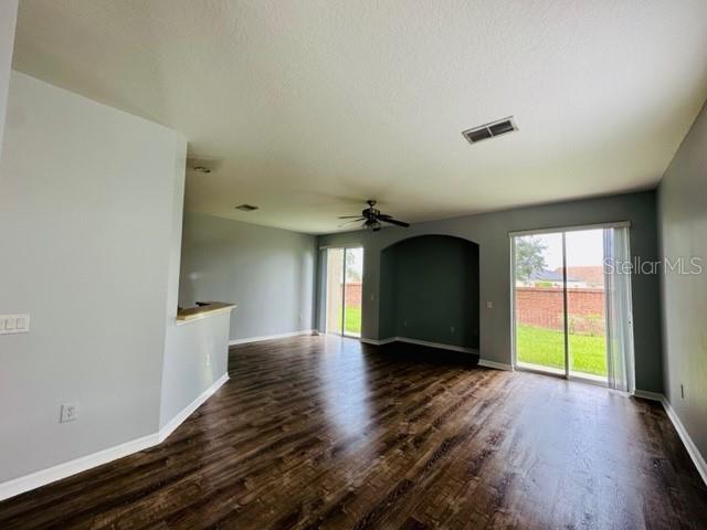 An open living area features dark wood-look flooring, light gray walls, and a sliding glass door — 1953 ESTANCIA CIRCLE UNIT C, KISSIMMEE, FL
