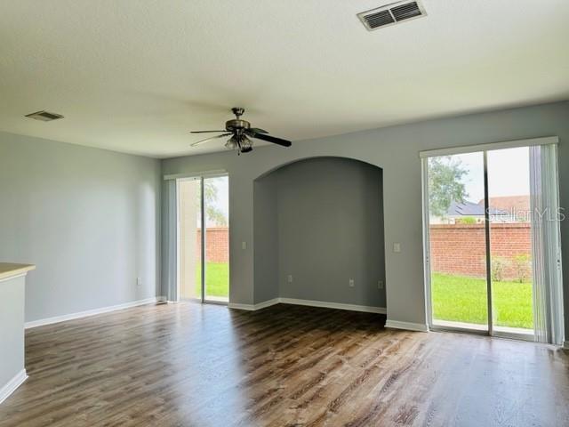 A living room with wood-look flooring, a ceiling fan, and sliding glass doors to a yard — 1953 ESTANCIA CIRCLE UNIT C, KISSIMMEE, FL