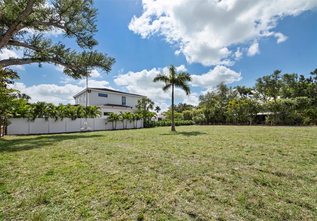 A large, grassy vacant lot features a single palm tree and a white privacy fence — 1703 ALTA VISTA STREET, SARASOTA, FL