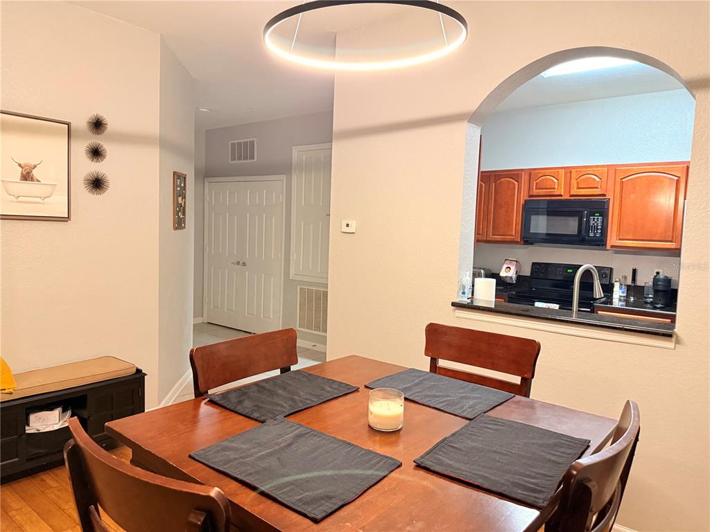 A dining area with a wooden table and chairs sits in front of an open kitchen — 8710 SARATOGA INLET DRIVE UNIT 203, ORLANDO, FL