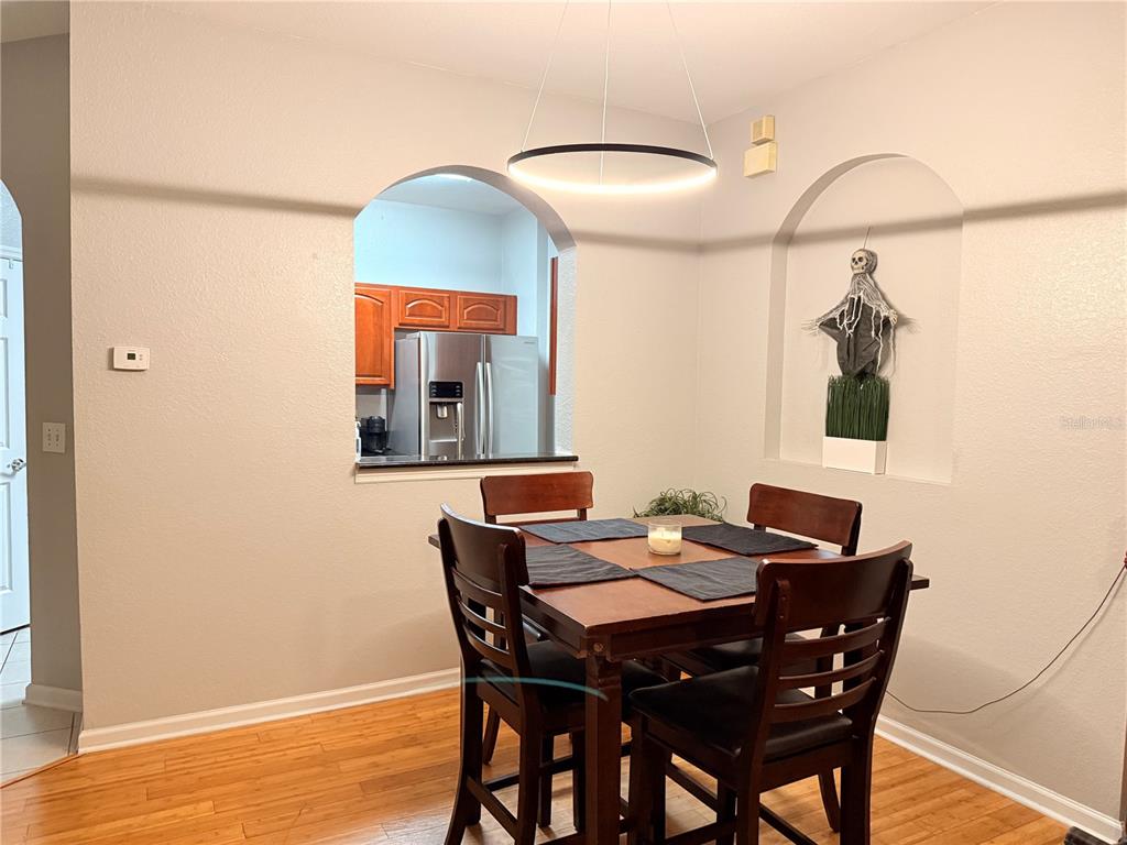 A dining area features a wooden table with four chairs, a modern light fixture, and an arched niche — 8710 SARATOGA INLET DRIVE UNIT 203, ORLANDO, FL