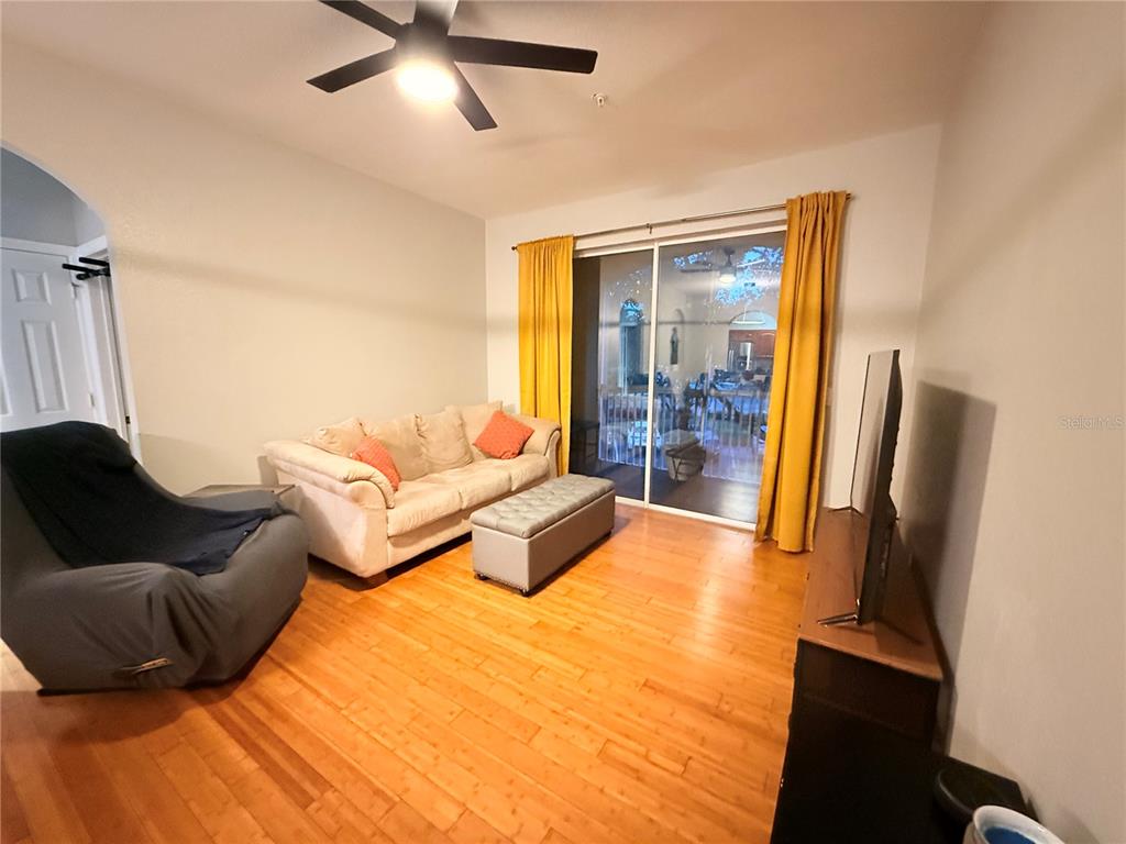 A living room features hardwood floors, a sofa, a recliner, and sliding glass patio doors — 8710 SARATOGA INLET DRIVE UNIT 203, ORLANDO, FL