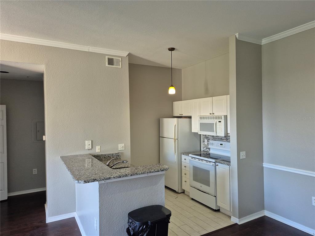 A kitchen with white cabinets, white appliances, and a granite-topped breakfast bar — 5146 NORTHRIDGE ROAD UNIT 309, SARASOTA, FL