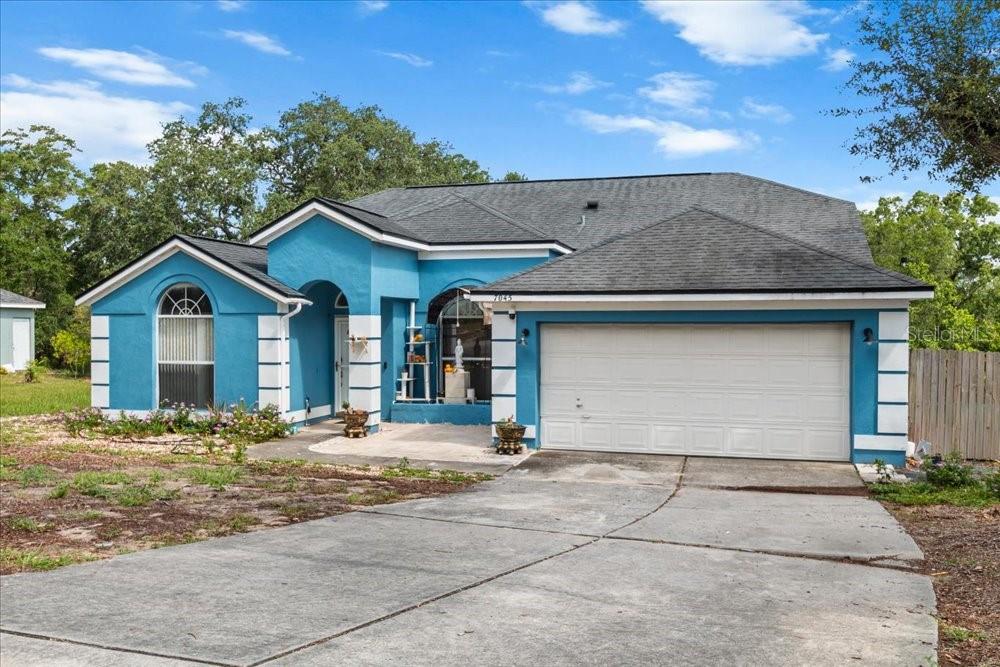 A single-story blue house with a white garage door and a concrete driveway — 7045 CORAL COVE DRIVE, ORLANDO, FL