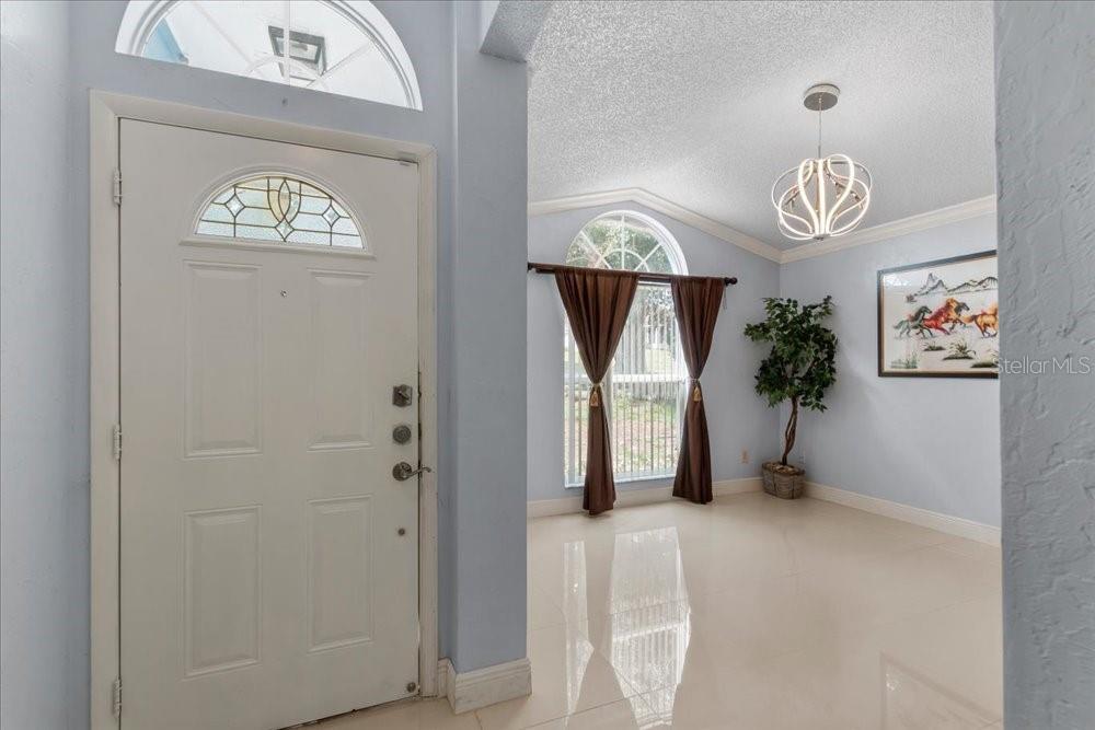 A bright entryway features a white front door, light tile floors, and arched windows — 7045 CORAL COVE DRIVE, ORLANDO, FL