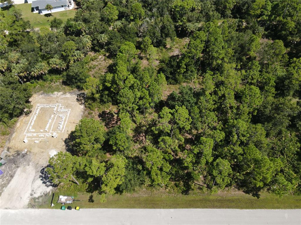 An aerial view shows a wooded lot with a concrete foundation poured for a new house — 27064 VALENCIA DRIVE, PUNTA GORDA, FL