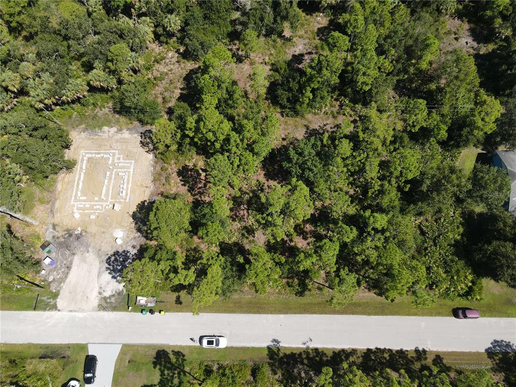 An aerial view shows a cleared building foundation on a wooded residential lot — 27064 VALENCIA DRIVE, PUNTA GORDA, FL