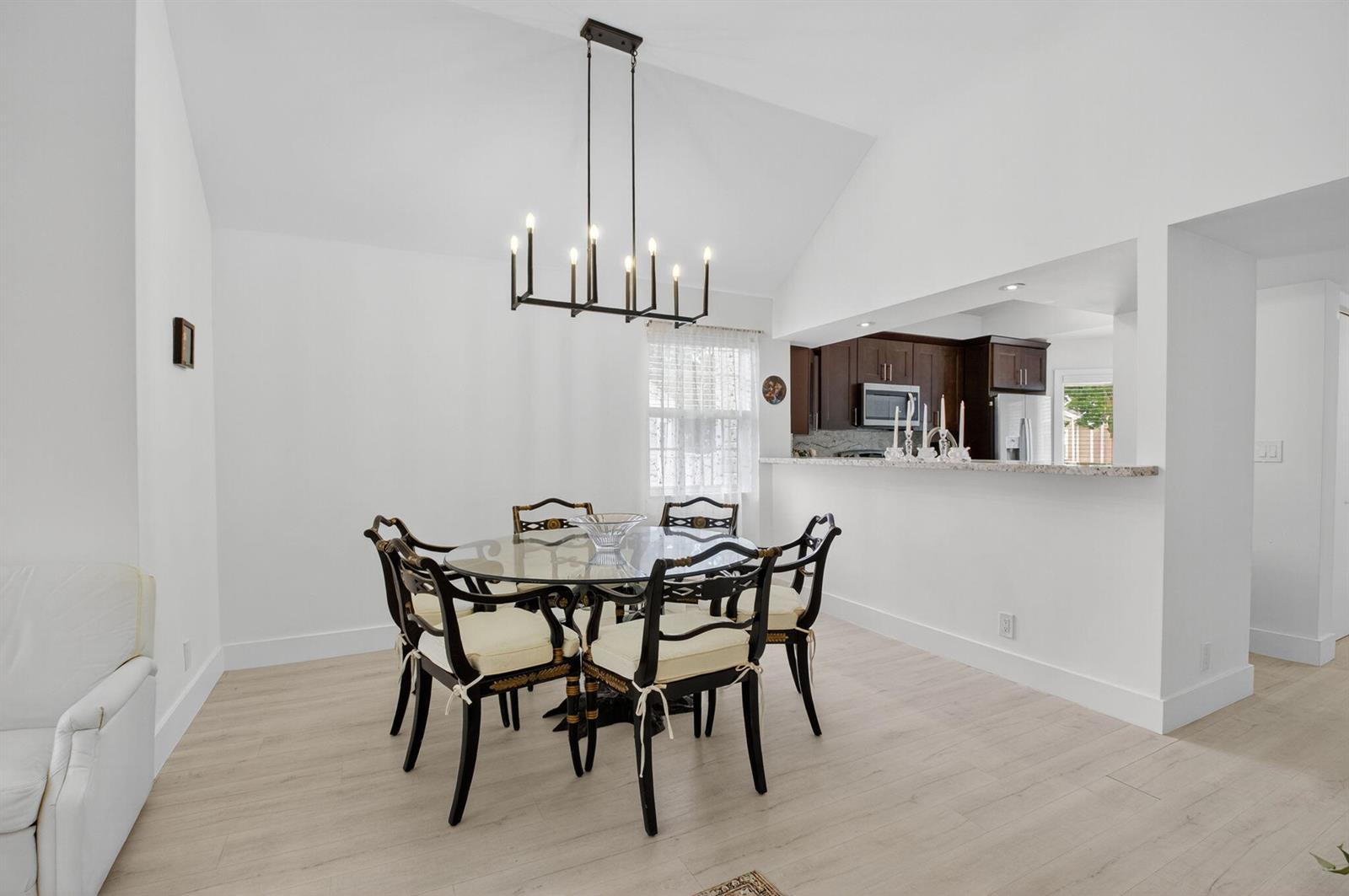 A dining area with a glass table, black chairs, and a chandelier near a kitchen — 5328 Buckhead Circle # 2020, Boca Raton FL 33486, BOCA RATON, FL