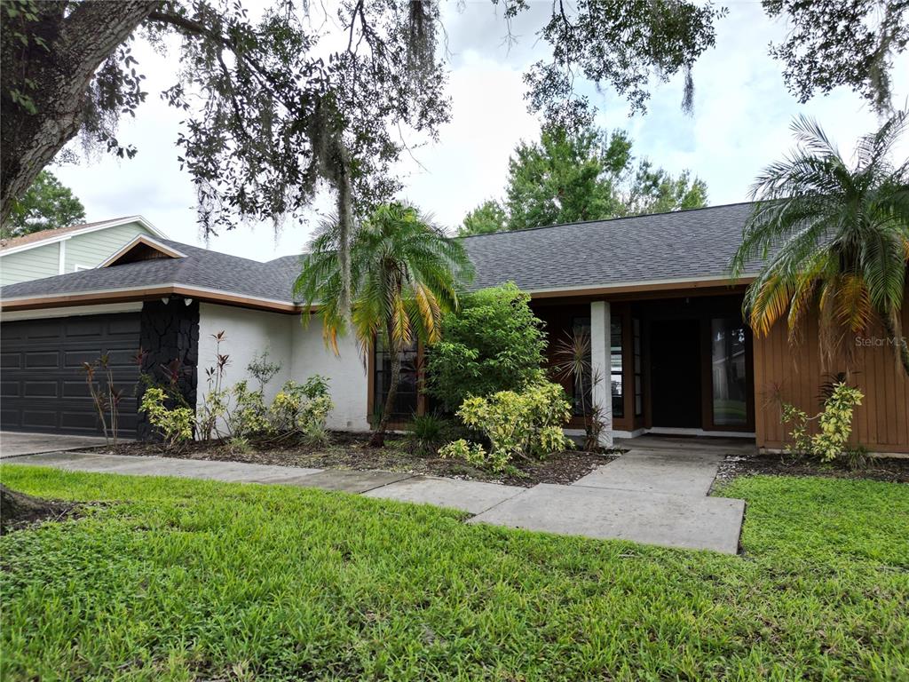 A single-story house with a dark garage door, white walls, and a front walkway — 4715 KEMBLE COURT, TAMPA, FL