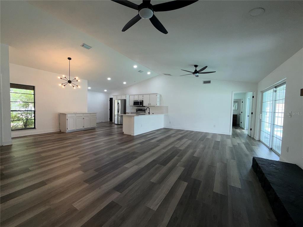 An open-concept living and kitchen area features wood-look flooring, white cabinetry, and vaulted ceilings — 4715 KEMBLE COURT, TAMPA, FL