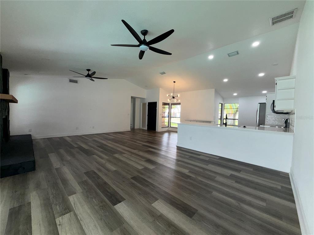 An open-concept living area features wood-look flooring, two ceiling fans, and a white kitchen island — 4715 KEMBLE COURT, TAMPA, FL