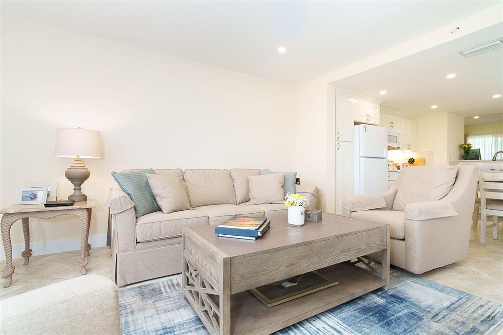 A living room features a beige sofa, matching armchair, wooden coffee table, and blue rug — 9200 LITTLE GASPARILLA ISLAND UNIT 403, PLACIDA, FL