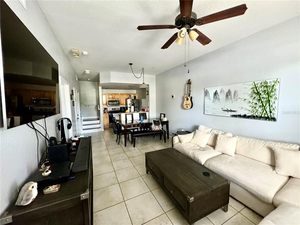 A living room with tile floors, a white sofa, and an open kitchen in back — 4000 SAN GALLO DRIVE UNIT 105, KISSIMMEE, FL