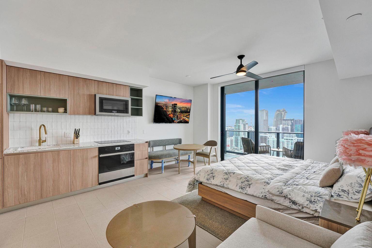 A studio apartment features a kitchenette, a bed, and a balcony overlooking a city skyline — 601 NE 1st Avenue # 4712, Miami FL 33132, MIAMI, FL