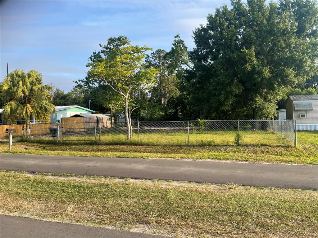 A fenced, grassy vacant lot features a single tree and is bordered by a paved road — 7018 S 51ST AVENUE, TAMPA, FL