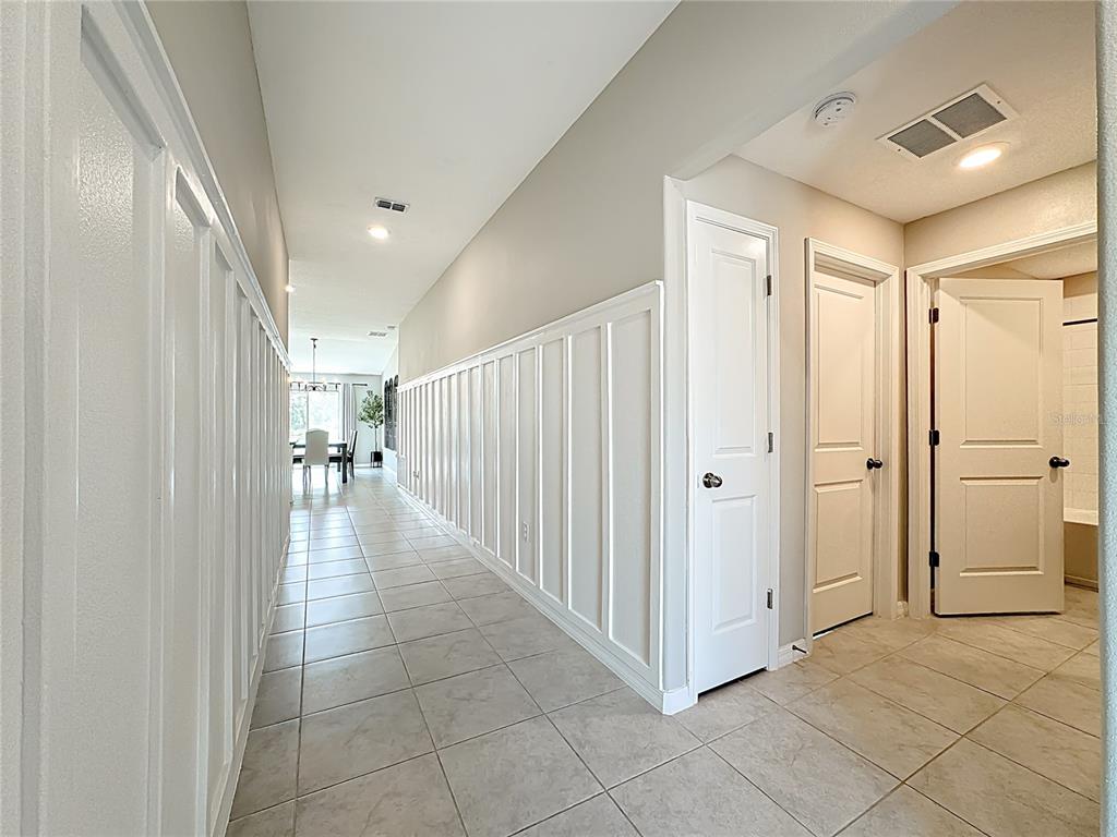 A long hallway with tiled floors and white board-and-batten wainscoting leads to a dining area — 4449 ETERNAL PRINCE DRIVE, SUN CITY CENTER, FL