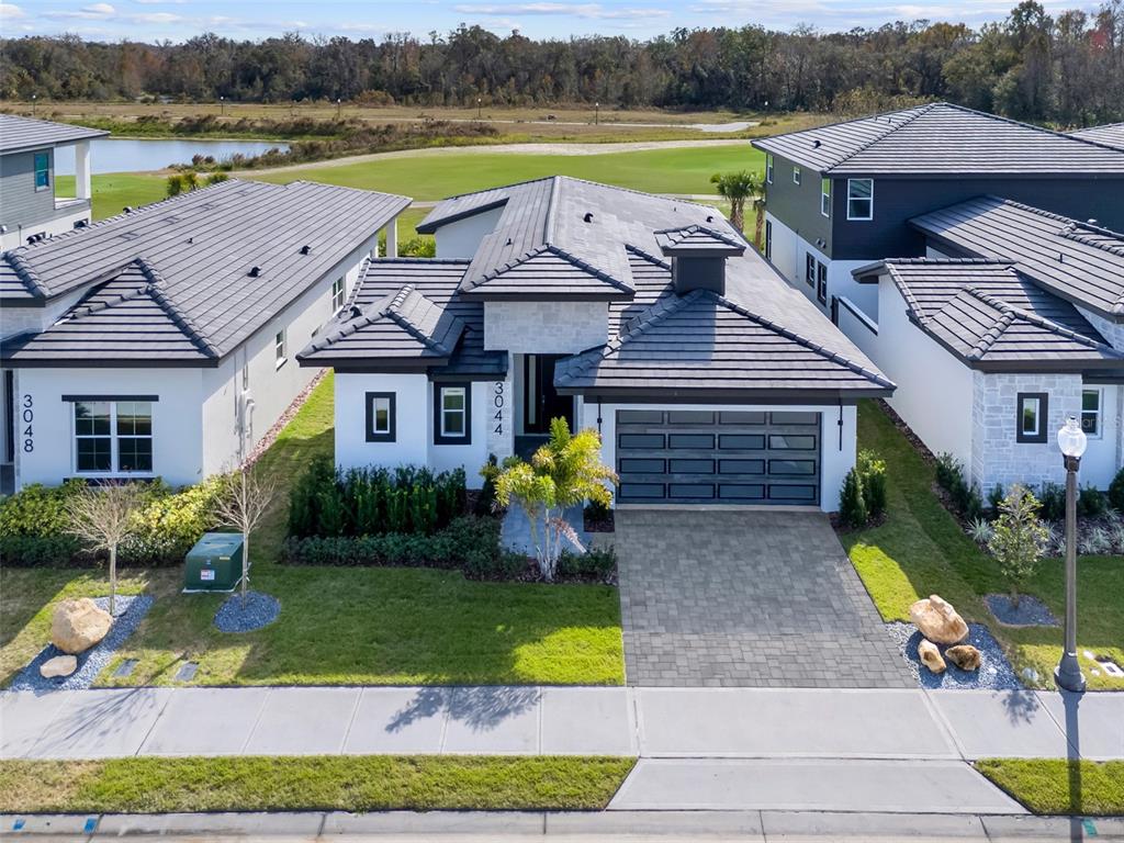 An aerial view shows a modern single-story house with a tiled roof and paved driveway — 3044 KENSINGTON AVENUE, DAVENPORT, FL