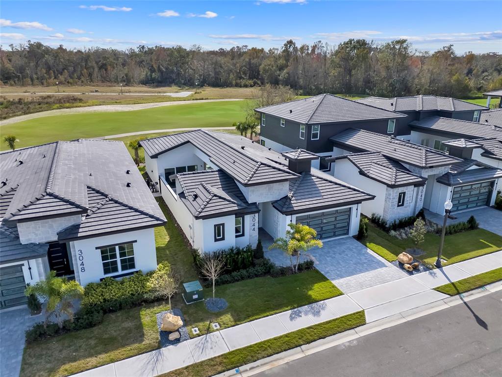 An aerial view shows several modern single-story houses with dark tile roofs and paved driveways — 3044 KENSINGTON AVENUE, DAVENPORT, FL