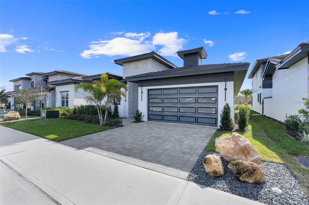 A modern single-story house with a paved driveway, a multi-panel garage door, and stone accents — 3044 KENSINGTON AVENUE, DAVENPORT, FL