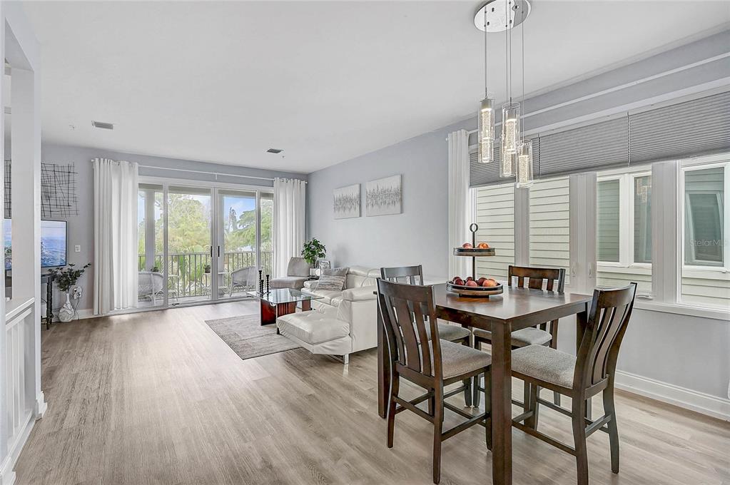 A dining area and living room with light wood floors, white walls, and a balcony view — 508 FOREST WAY UNIT 508, LONGBOAT KEY, FL