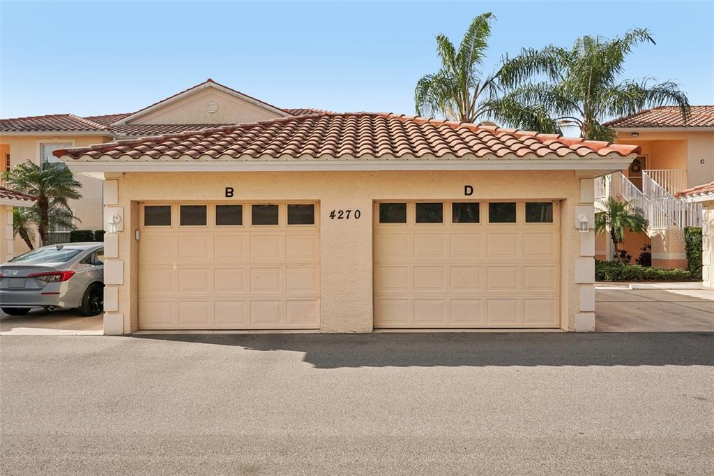 A detached two-car garage with beige doors labeled B and D under a tiled roof — 4270 VICENZA DRIVE UNIT D40, VENICE, FL