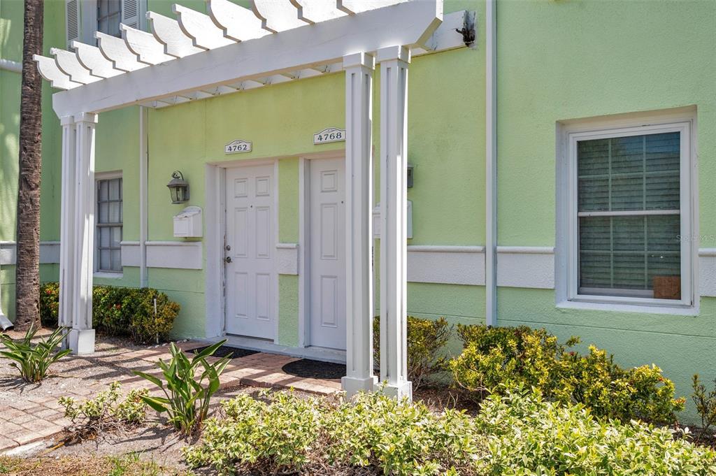 A light green building exterior features two white doors under a white wooden pergola — 4768 COQUINA KEY DRIVE SE, ST PETERSBURG, FL