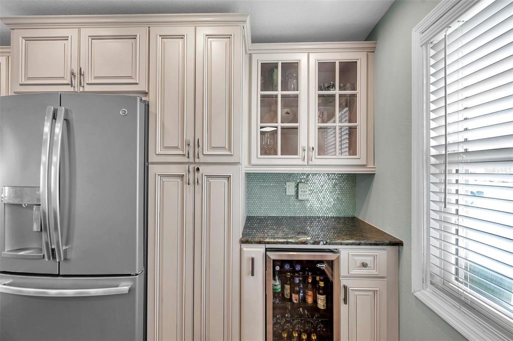 A kitchen features light-colored cabinetry, a stainless steel refrigerator, and a built-in wine cooler — 4768 COQUINA KEY DRIVE SE, ST PETERSBURG, FL