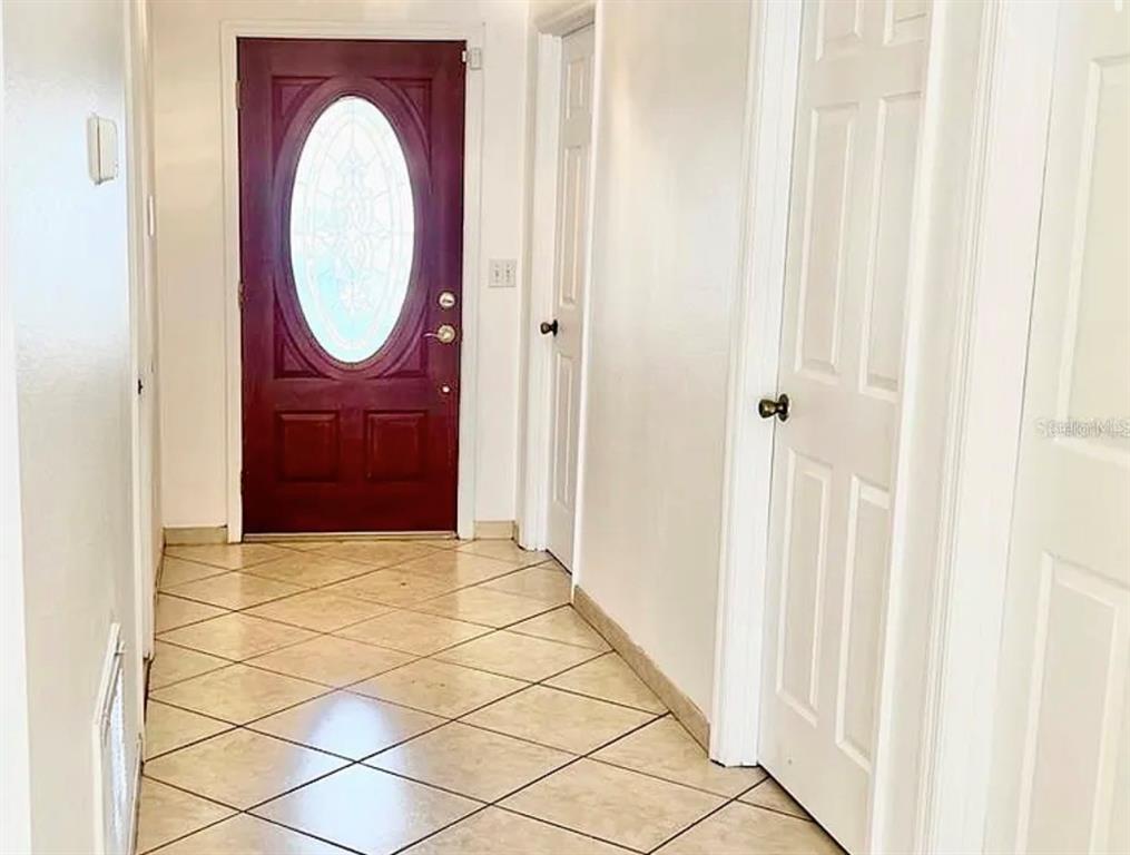 A tiled entryway features a dark wood front door with an oval glass insert — 13158 ODYSSEY LAKE WAY, ORLANDO, FL