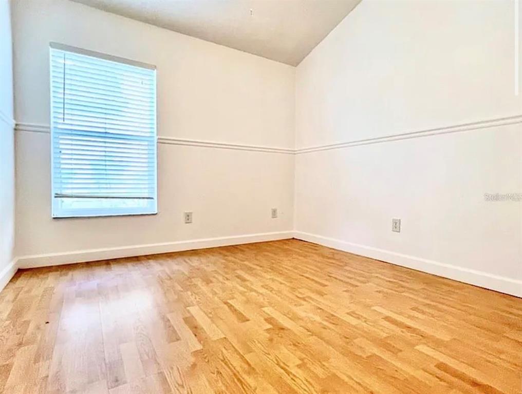 An empty room features light hardwood flooring, white walls with chair rail molding, and a window — 13158 ODYSSEY LAKE WAY, ORLANDO, FL