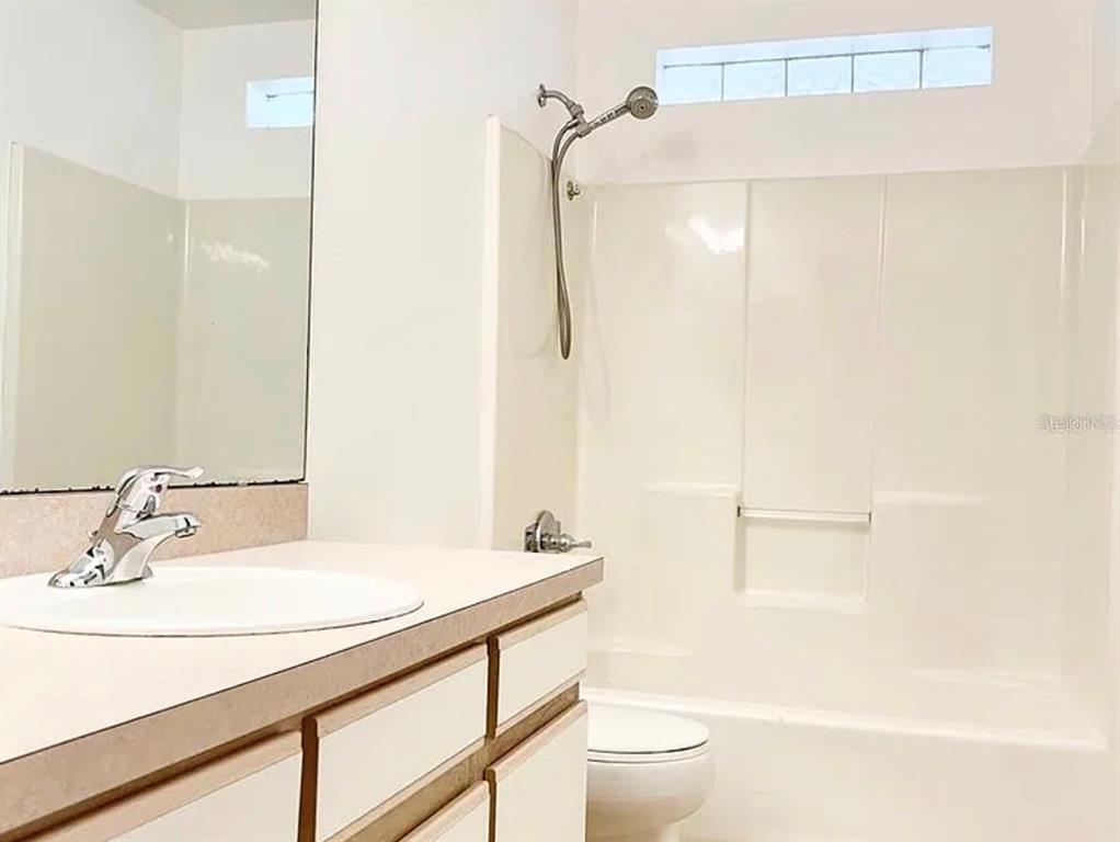 A bathroom features a white vanity, a mirror, a toilet, and a shower-tub combination — 13158 ODYSSEY LAKE WAY, ORLANDO, FL