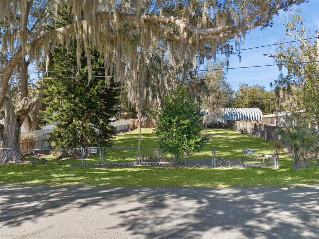 A fenced, grassy vacant lot is shaded by large trees with hanging Spanish moss — 1724 EVERGREEN STREET, KISSIMMEE, FL
