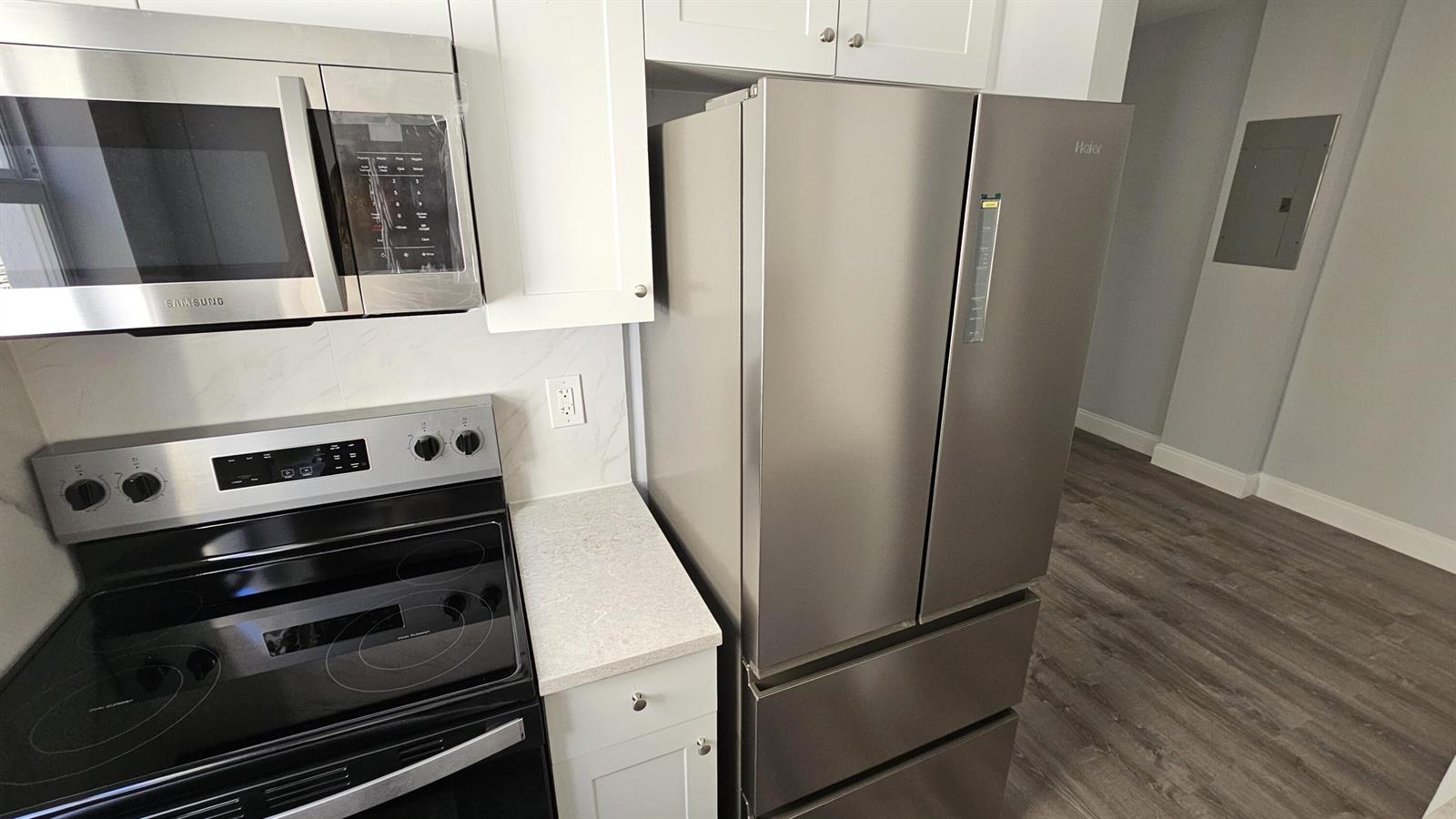 A kitchen with white cabinets, stainless steel appliances, and wood-look flooring in an open room — 1142 SW 4th Street # 9, Miami FL 33130, MIAMI, FL