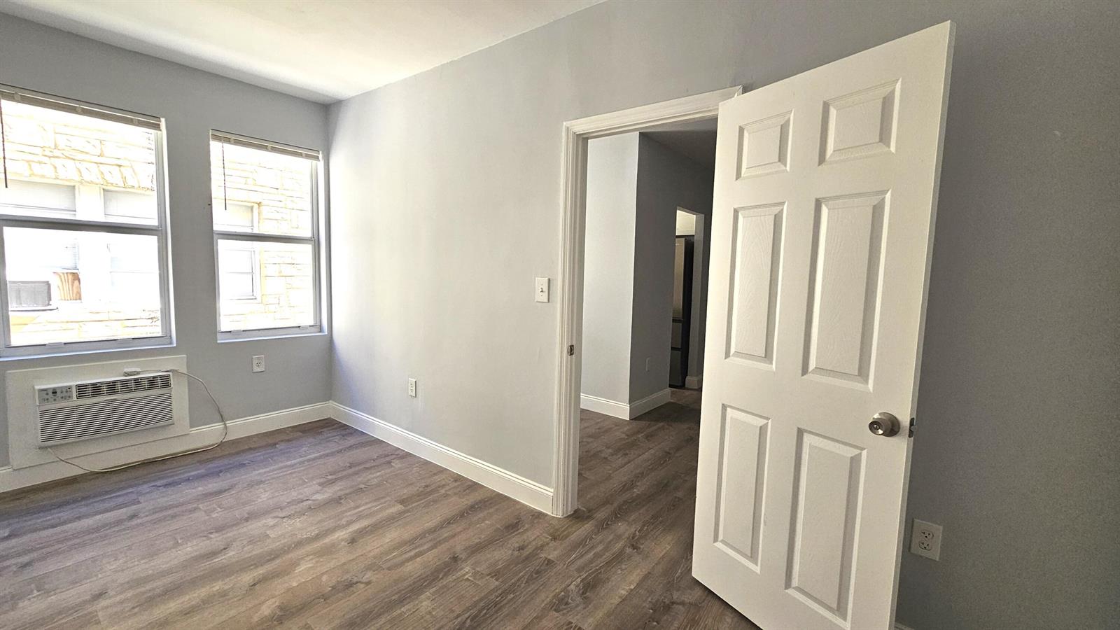 A room with gray wood-look flooring, two sets of white closet doors, and one interior door — 1142 SW 4th Street # 9, Miami FL 33130, MIAMI, FL