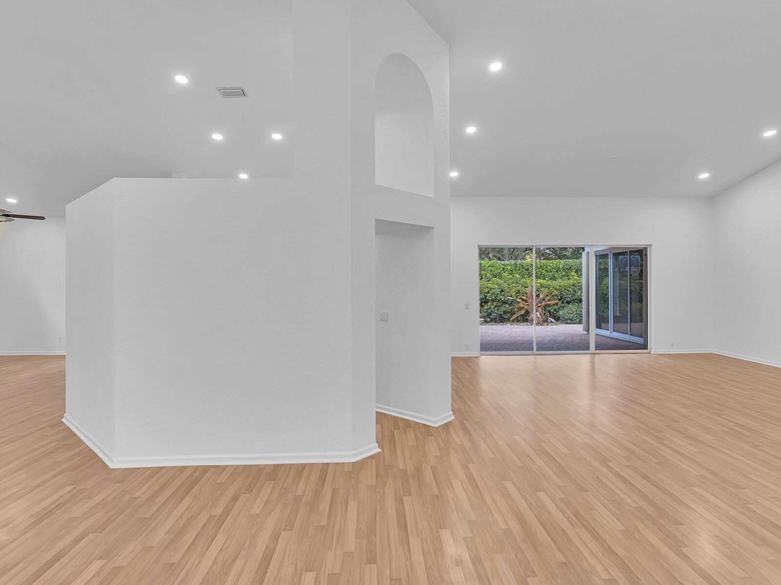An empty living area features white walls, light wood flooring, recessed lighting, and sliding glass doors — 3420 Washington Lane, Cooper City FL 33026, COOPER CITY, FL