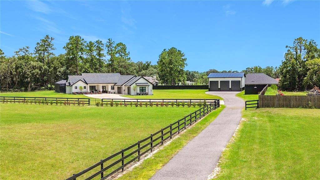 A white house with a black roof sits on a grassy lot with a driveway — 7525 NE 58TH AVENUE, ANTHONY, FL