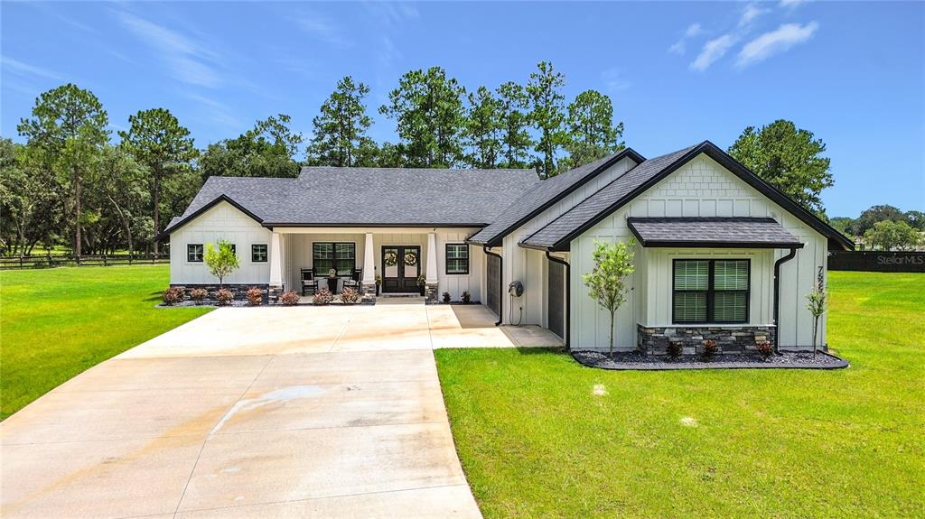 A modern white farmhouse with a dark roof and a concrete driveway sits on grass — 7525 NE 58TH AVENUE, ANTHONY, FL