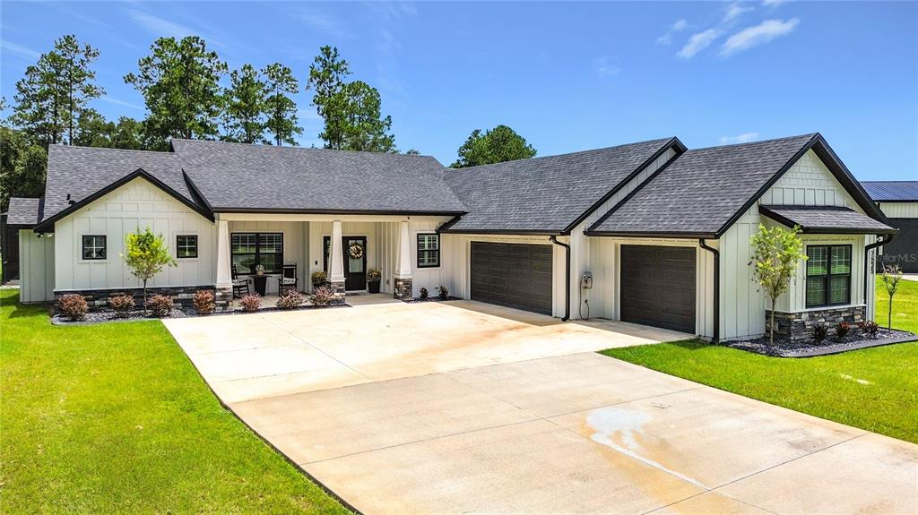 A white farmhouse-style house with a dark roof, two garage doors, and a concrete driveway — 7525 NE 58TH AVENUE, ANTHONY, FL