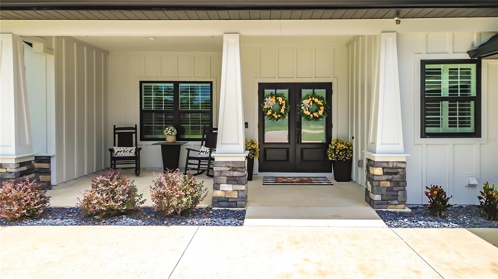 A front porch features a double door entrance, two rocking chairs, and stone-based pillars — 7525 NE 58TH AVENUE, ANTHONY, FL